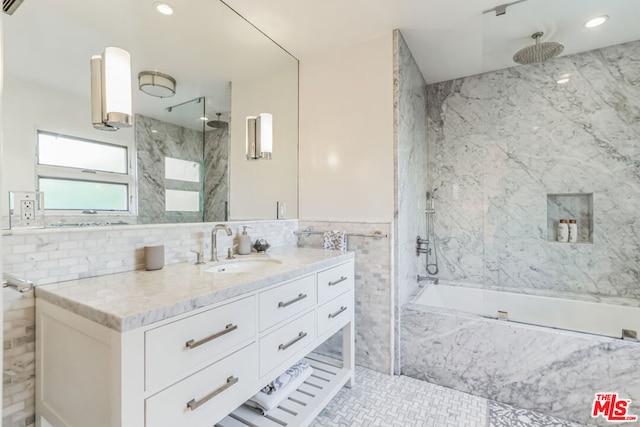 bathroom featuring tile walls, vanity, and tiled shower / bath