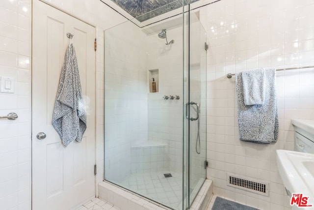 bathroom with tile walls, sink, and walk in shower