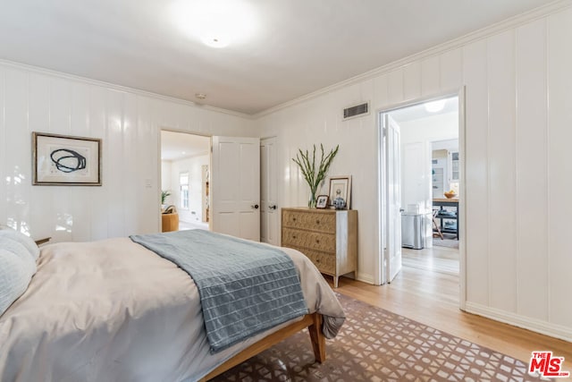 bedroom with ornamental molding and light wood-type flooring