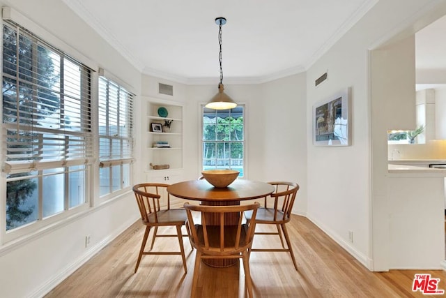 dining room featuring ornamental molding, built in features, and light wood-type flooring