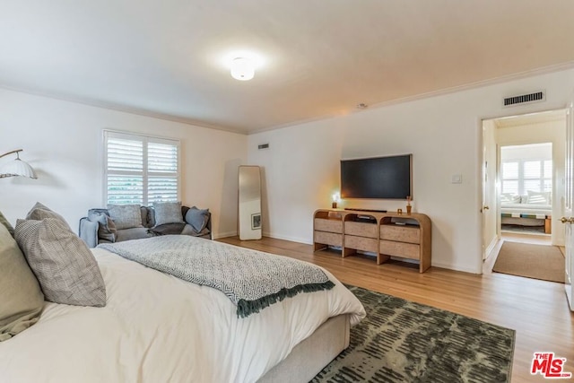 bedroom featuring crown molding, wood-type flooring, and multiple windows