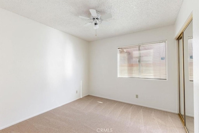 carpeted spare room featuring a textured ceiling and ceiling fan