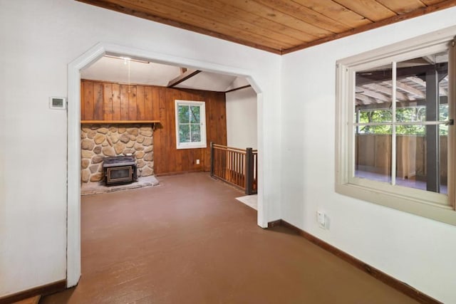 unfurnished living room featuring concrete flooring, a wealth of natural light, wooden ceiling, and wooden walls