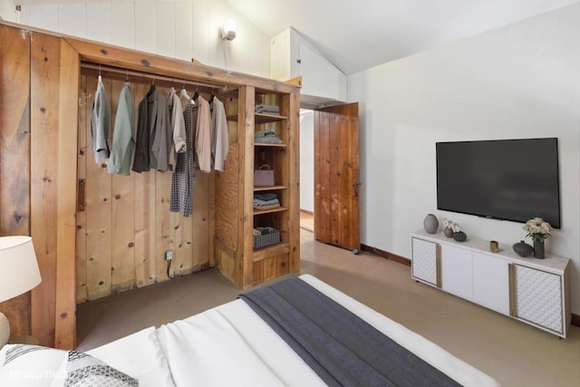 bedroom with lofted ceiling, wooden walls, and light colored carpet