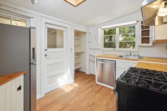 kitchen with butcher block countertops, stainless steel appliances, sink, and white cabinets