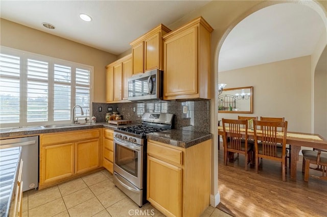 kitchen featuring light brown cabinetry, sink, light tile patterned floors, decorative backsplash, and stainless steel appliances