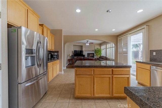 kitchen featuring a center island, light brown cabinetry, tasteful backsplash, light tile patterned floors, and stainless steel appliances