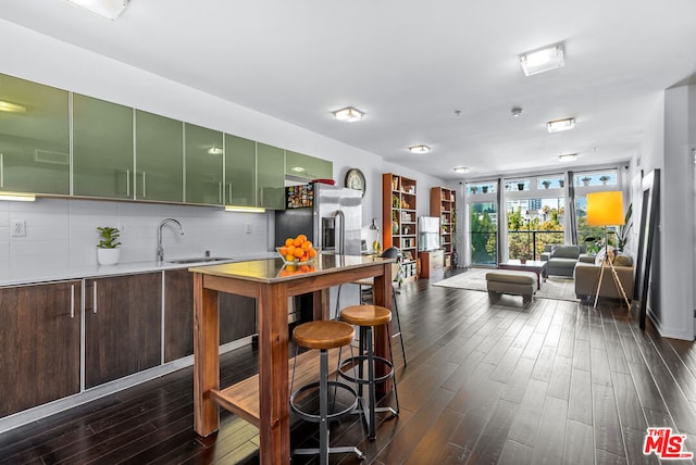 kitchen with decorative backsplash, stainless steel refrigerator with ice dispenser, sink, expansive windows, and dark hardwood / wood-style flooring