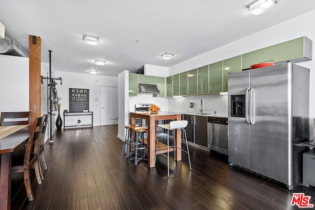 kitchen featuring dark wood-type flooring, stainless steel appliances, decorative backsplash, sink, and green cabinetry