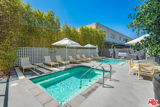 view of swimming pool featuring a community hot tub, a patio area, and grilling area