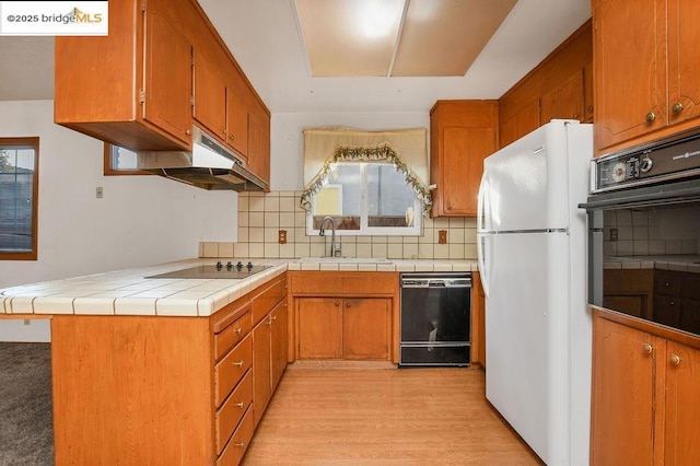 kitchen with sink, black appliances, tasteful backsplash, and a wealth of natural light