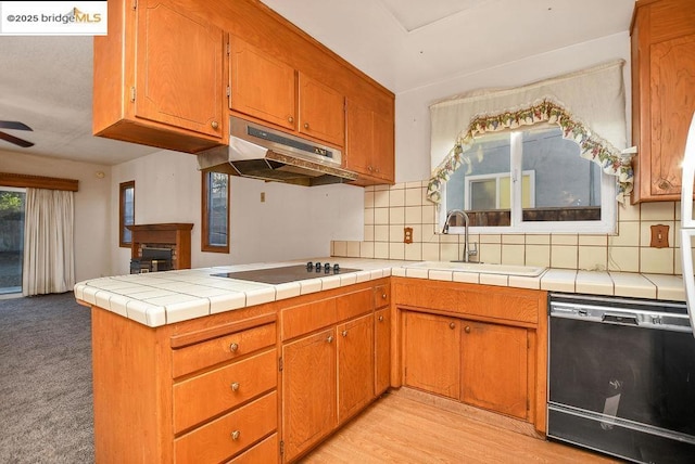 kitchen with black appliances, decorative backsplash, sink, kitchen peninsula, and tile countertops