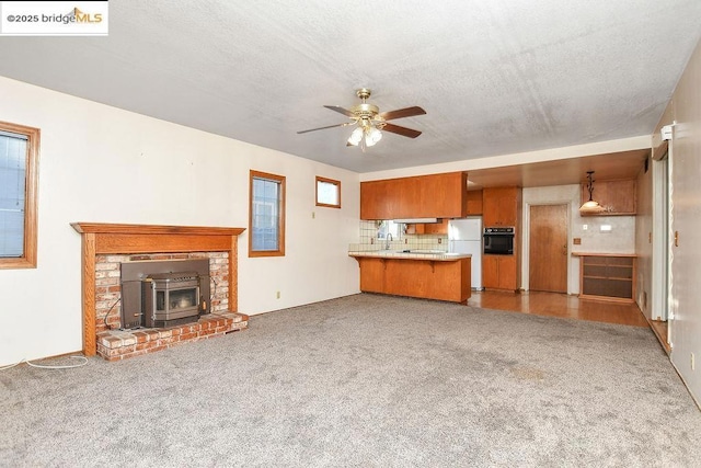 unfurnished living room featuring ceiling fan, a textured ceiling, and dark colored carpet