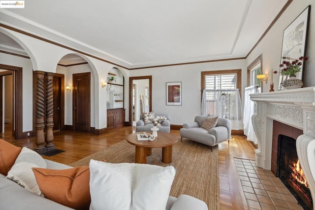 living room featuring ornamental molding, light wood-type flooring, and a tile fireplace