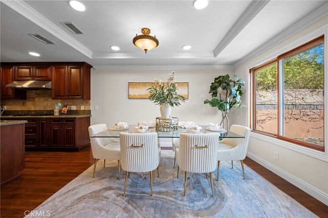 dining space featuring ornamental molding, a raised ceiling, and dark hardwood / wood-style flooring