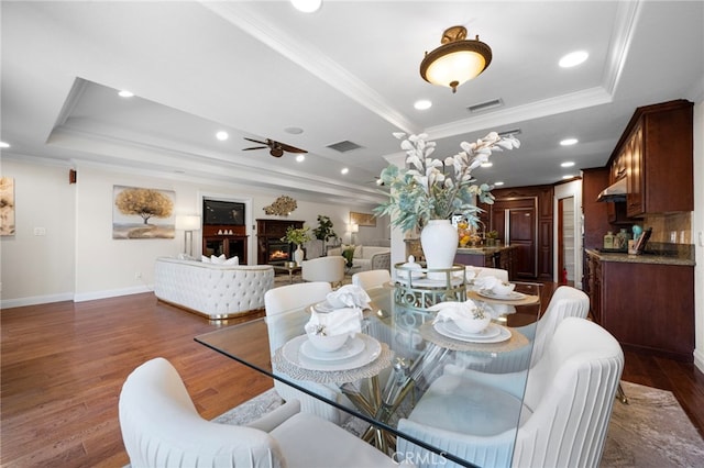 dining space with dark hardwood / wood-style flooring, ornamental molding, and a raised ceiling