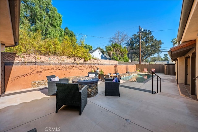 view of patio with a fenced in pool and a fire pit