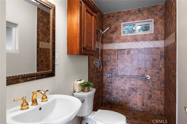 bathroom featuring sink, toilet, and tiled shower