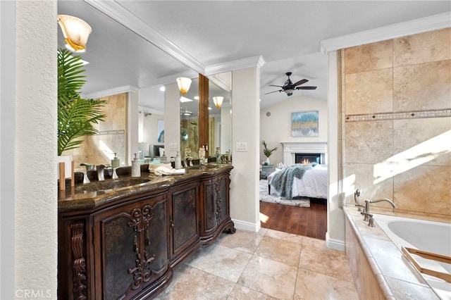 bathroom with tiled tub, ornamental molding, lofted ceiling, and vanity