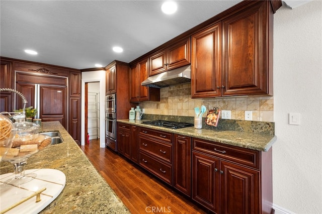 kitchen featuring tasteful backsplash, light stone counters, black gas stovetop, dark hardwood / wood-style floors, and stainless steel double oven