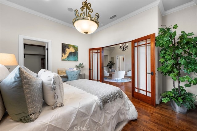 bedroom with a walk in closet, dark hardwood / wood-style flooring, and crown molding