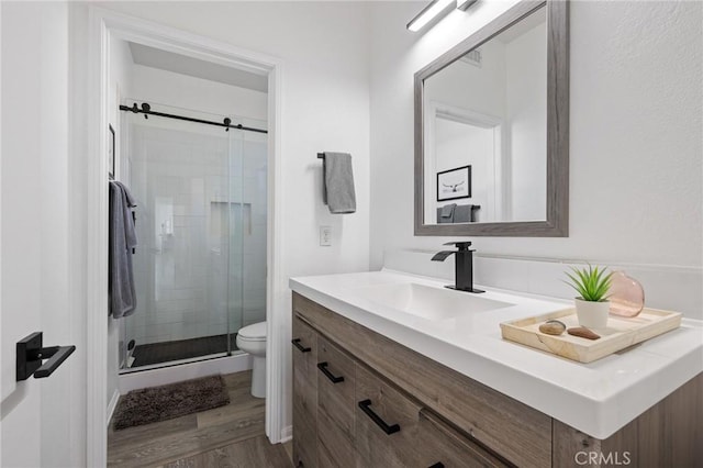 full bathroom with a stall shower, vanity, toilet, and wood finished floors