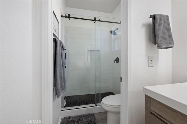 full bathroom featuring a stall shower, vanity, and toilet