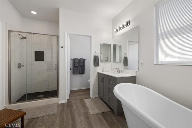 bathroom with a freestanding tub, a stall shower, wood finished floors, and vanity