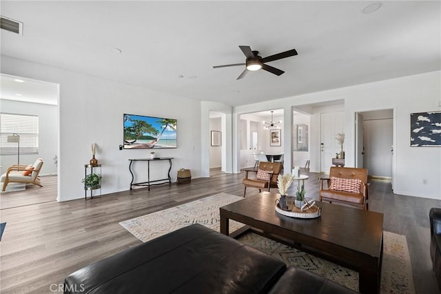 living room featuring visible vents, wood finished floors, and ceiling fan with notable chandelier