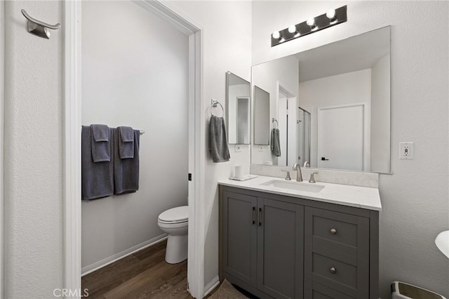 full bath featuring vanity, wood finished floors, toilet, and baseboards