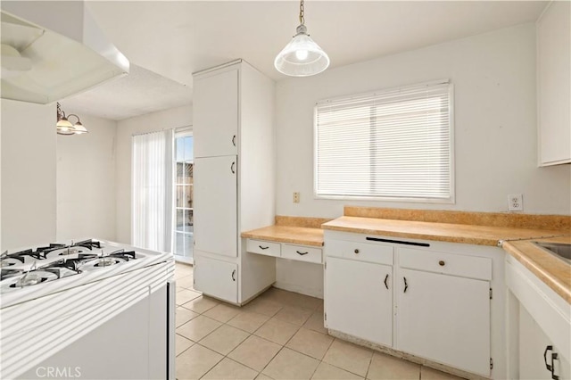 kitchen with white cabinets, hanging light fixtures, white range with gas cooktop, and light tile patterned flooring