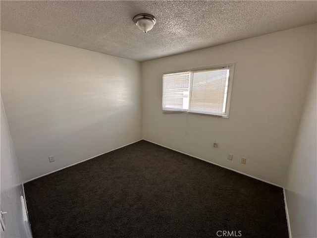 spare room featuring a textured ceiling and dark colored carpet