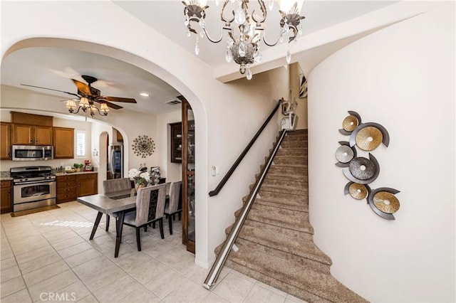 stairway featuring ceiling fan with notable chandelier and tile patterned flooring