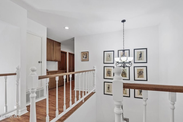 hallway with hardwood / wood-style floors and a notable chandelier