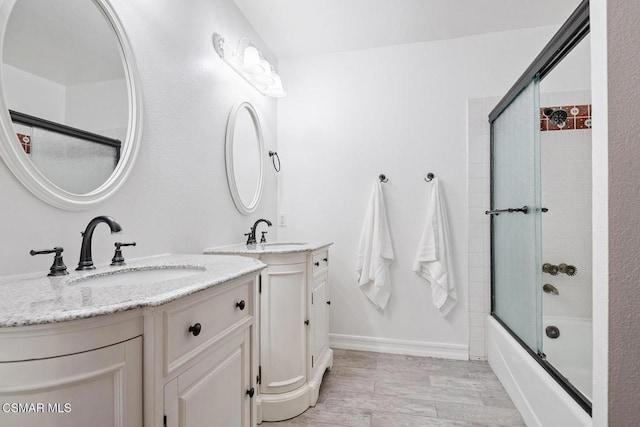 bathroom featuring bath / shower combo with glass door and vanity