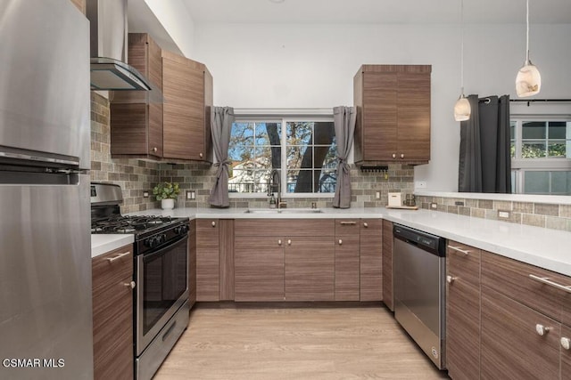 kitchen with tasteful backsplash, wall chimney exhaust hood, appliances with stainless steel finishes, and sink