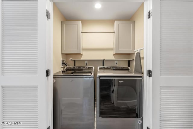 clothes washing area featuring cabinets and separate washer and dryer