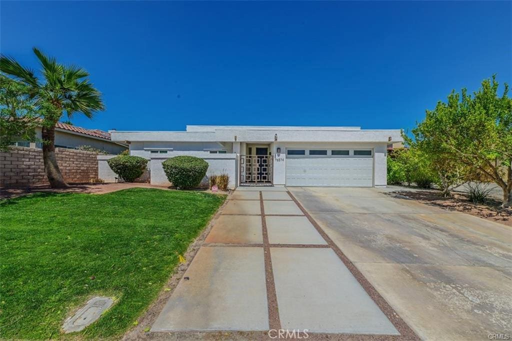 single story home featuring a garage and a front lawn