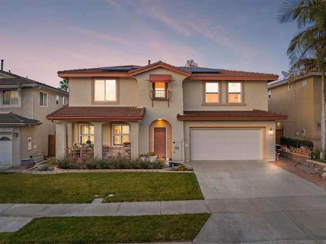 mediterranean / spanish-style house featuring a garage, covered porch, a lawn, and solar panels