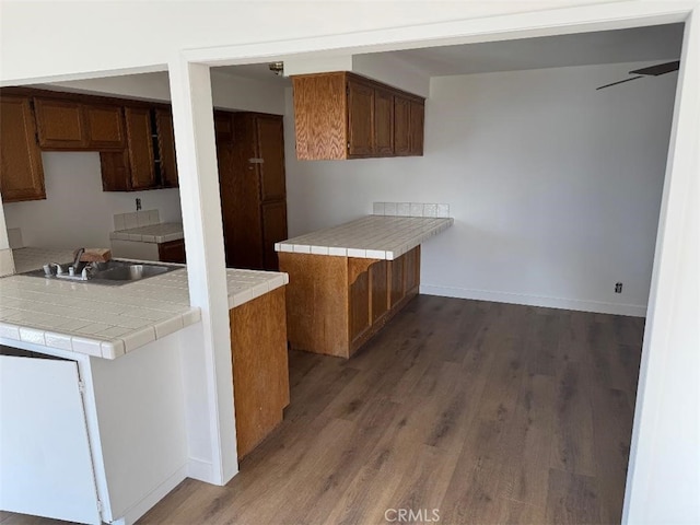 kitchen featuring sink, dark hardwood / wood-style flooring, kitchen peninsula, and tile countertops