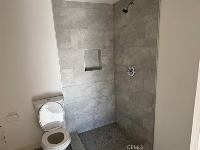 bathroom featuring toilet and a tile shower