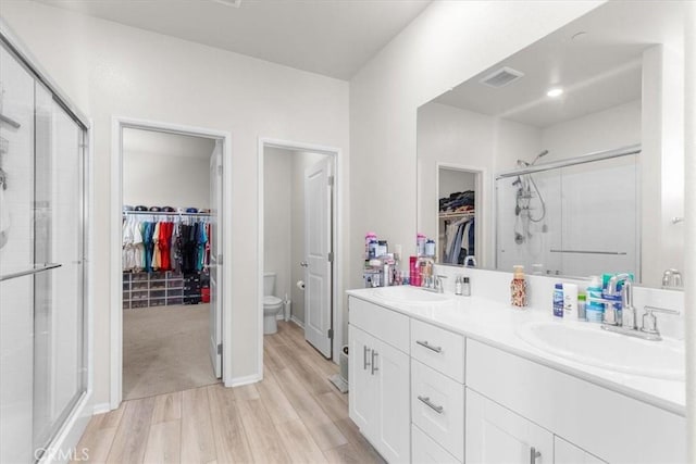 bathroom featuring vanity, hardwood / wood-style flooring, a shower with door, and toilet