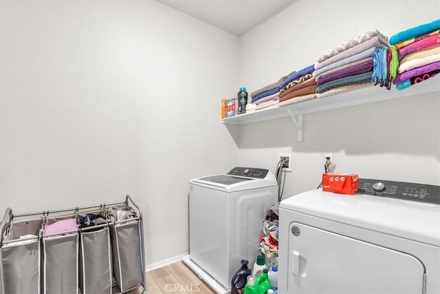 clothes washing area with light hardwood / wood-style floors and washer and dryer