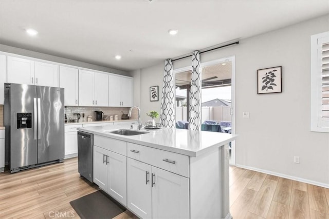 kitchen with sink, white cabinetry, light wood-type flooring, appliances with stainless steel finishes, and an island with sink