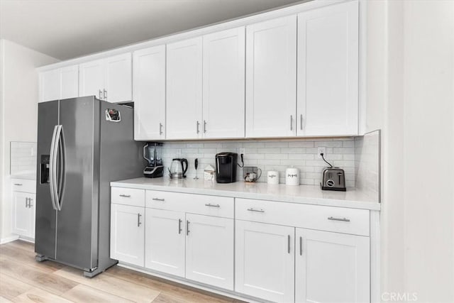 kitchen featuring tasteful backsplash, white cabinets, and stainless steel fridge with ice dispenser