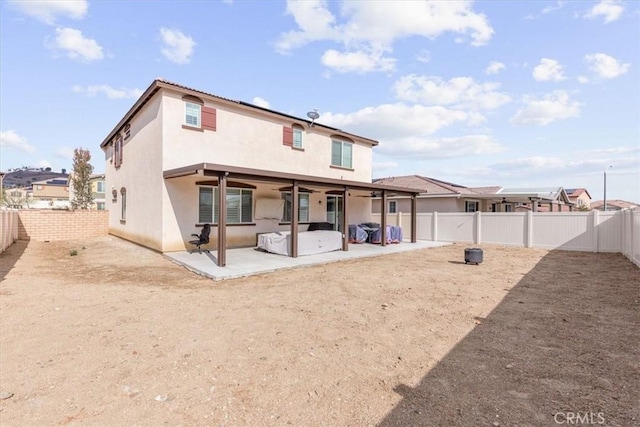 back of property with a hot tub and a patio