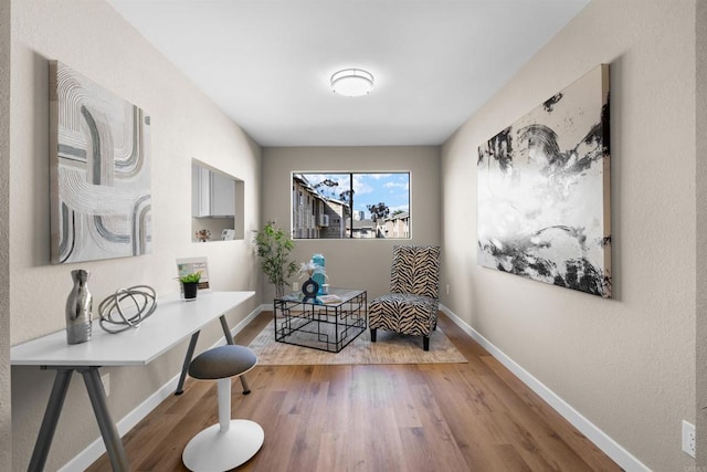 living area with baseboards and wood finished floors