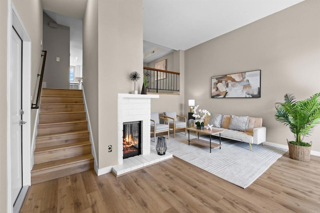 living room with wood finished floors, a fireplace, baseboards, and stairs