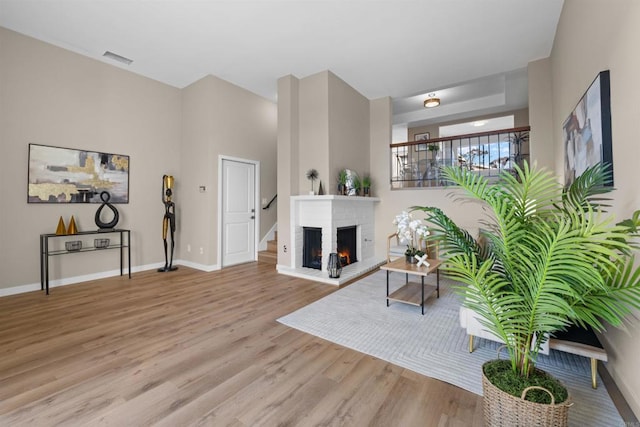 living room featuring a fireplace, wood finished floors, visible vents, and baseboards