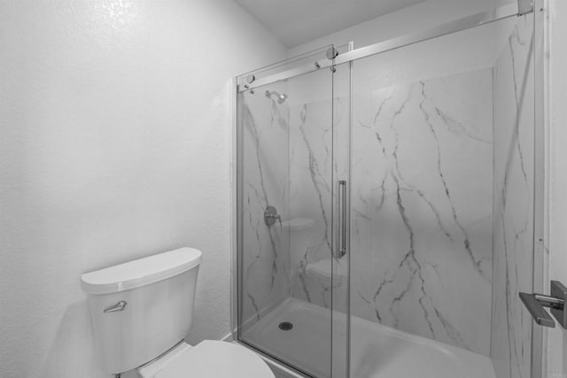 bathroom featuring toilet and a marble finish shower